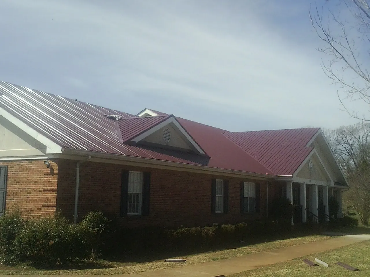 Red metal roof with gabled entries on a long brick building in Wauseon