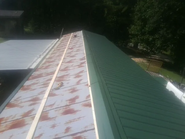 Old rusted panels beside newly installed green metal roofing — Wind Damage Roof Repair by Roofing Brothers in Wauseon