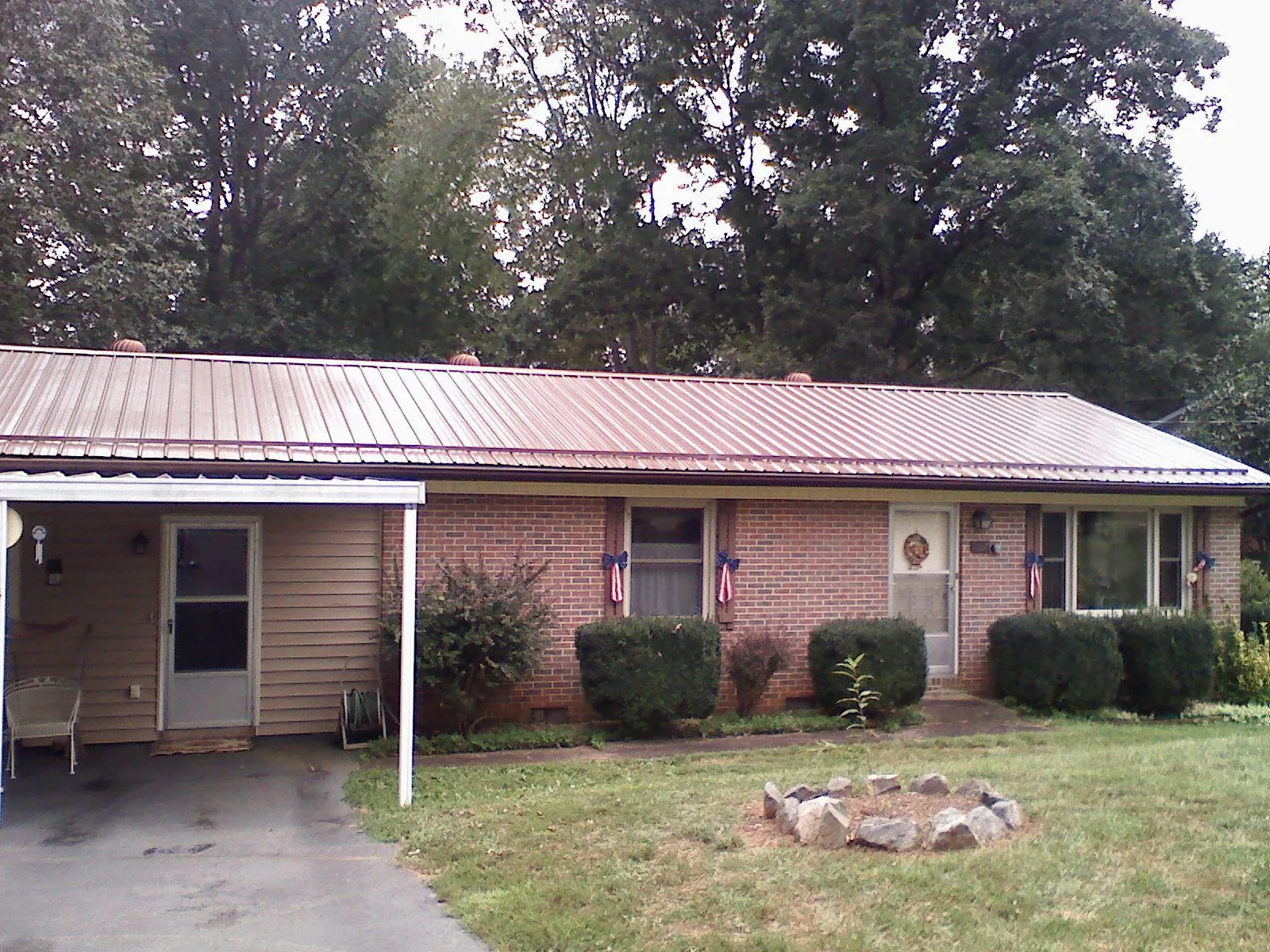 Bronze metal roof and carport on a brick ranch home — Roof Repair work by our crew in Wauseon