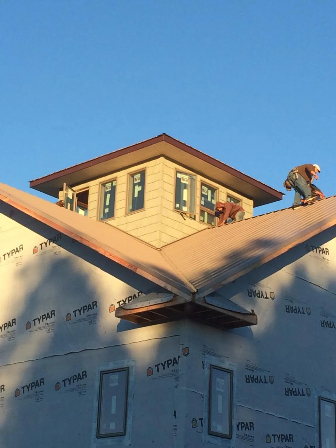 Roofers working around a rooftop cupola on a new metal roof at sunset — Roof Waterproofing in Wauseon by Roofing Brothers